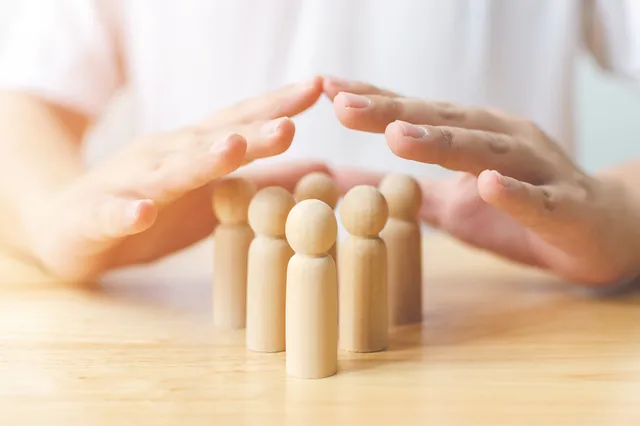 Protection people health and insurance concept. Hand shield protect wooden human on table